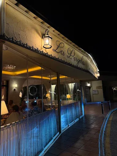 The illuminated La Pergola sign along the terrace at night