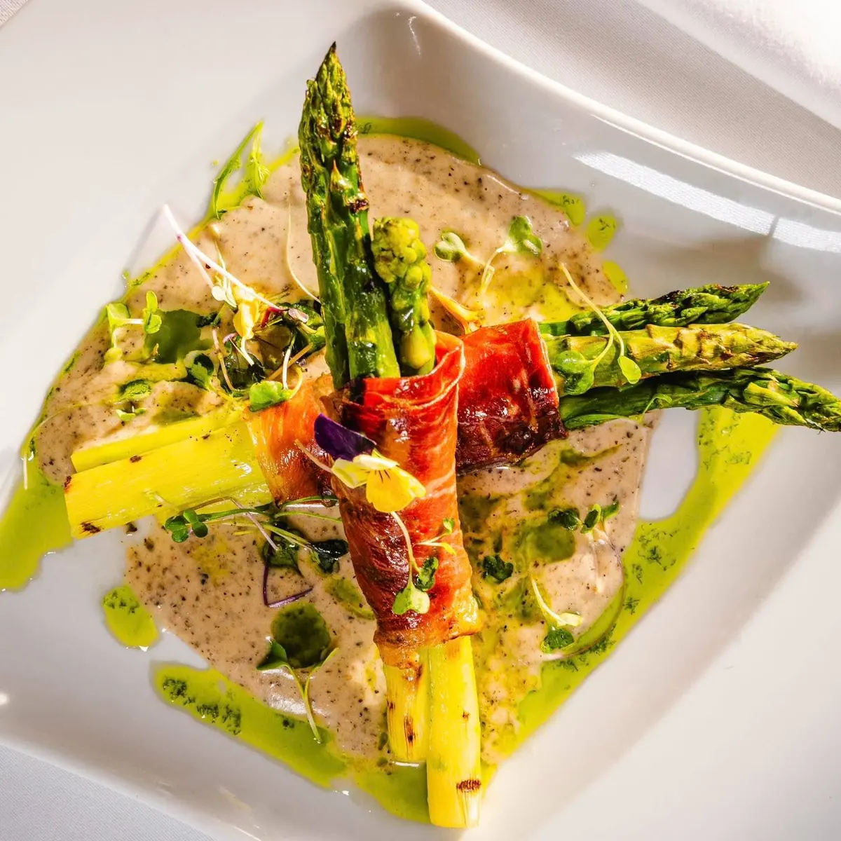 Grilled asparagus wrapped in Parma ham over a truffle sauce