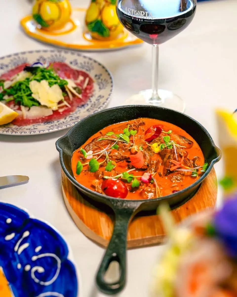 A skillet dish and beef carpaccio, shared at the table