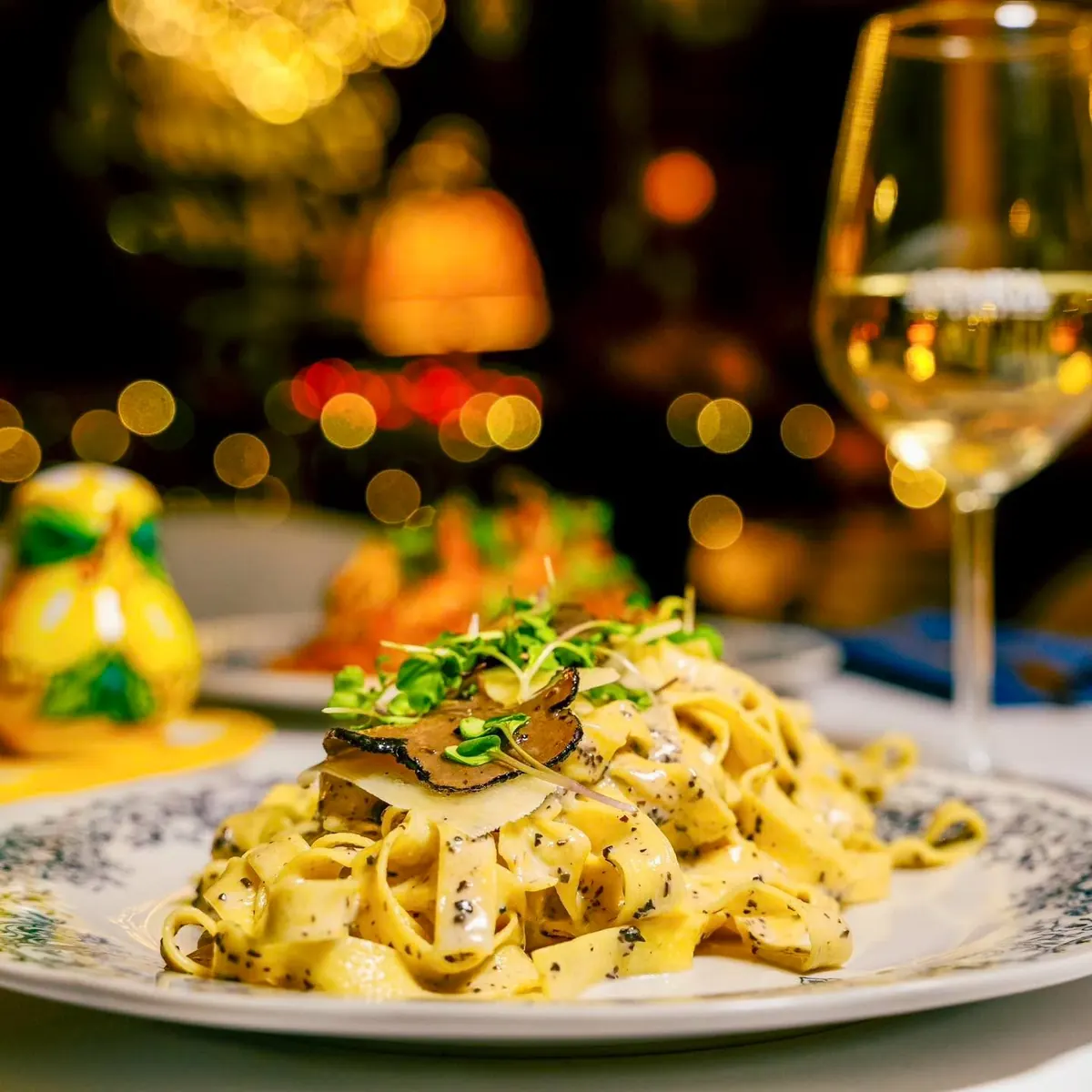 Tagliatelle with shaved black truffle, a glass of white wine behind