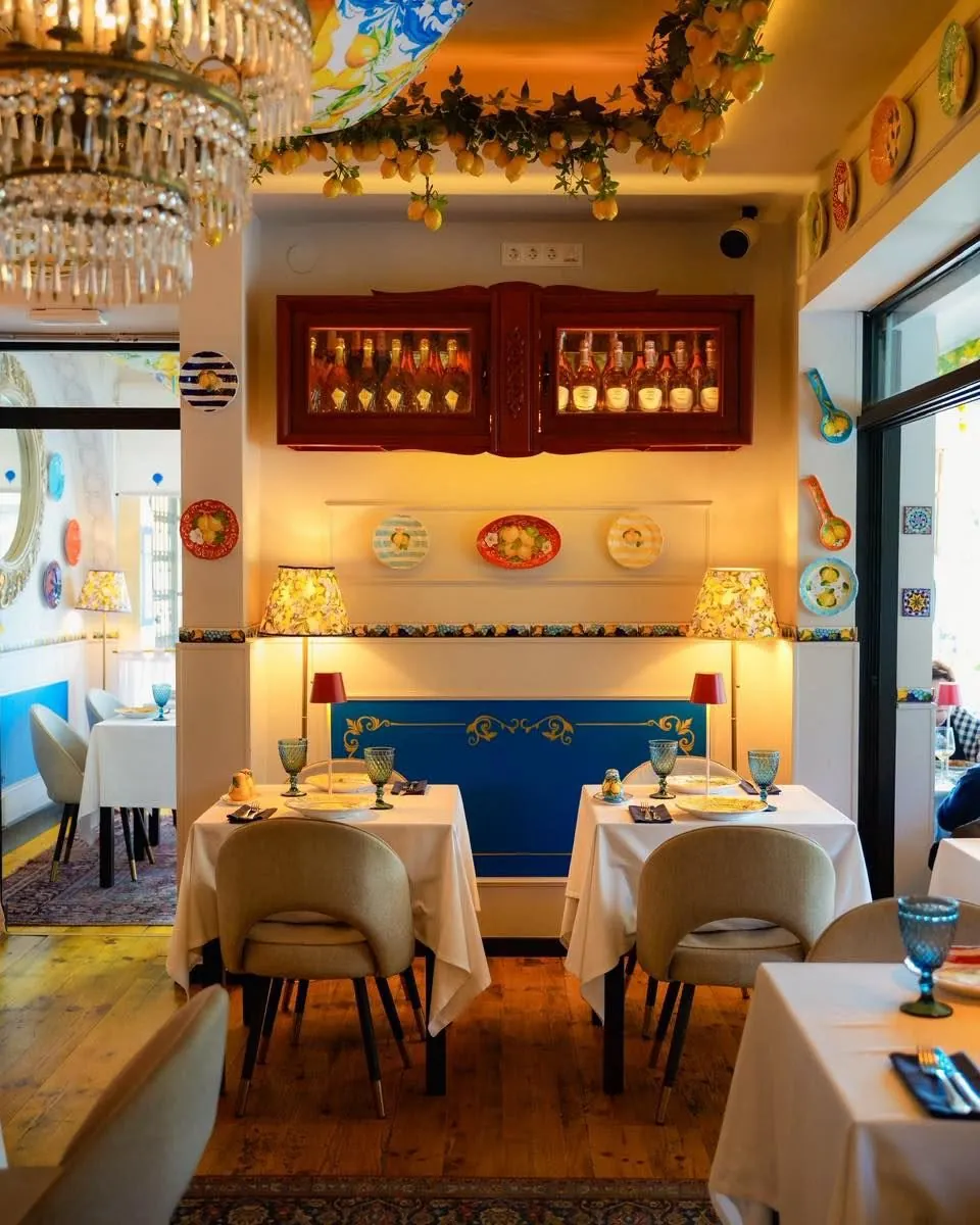 The dining room: white tables, lemon garlands overhead and a blue panelled wall with painted plates